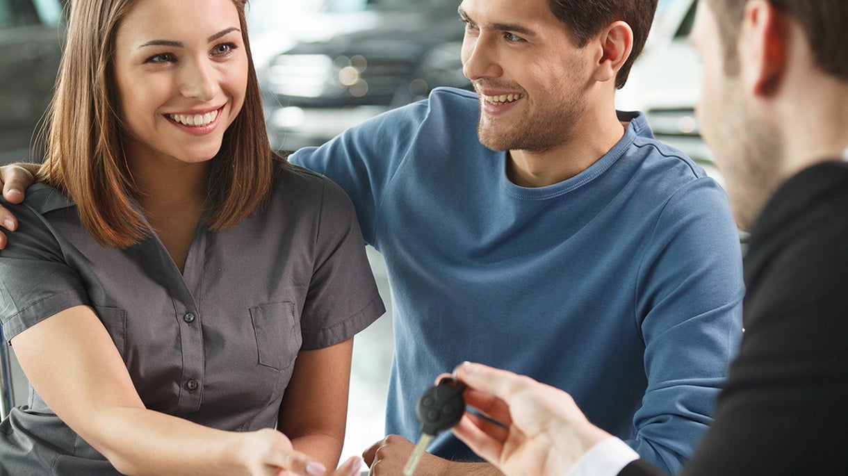 Smiling couple getting car keys at showroom